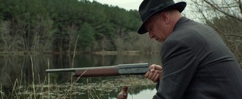 Movie still from “The Highwaymen” (2019), directed by John Lee Hancock – A man in a hat is holding a rifle; Medium shot, Low angle