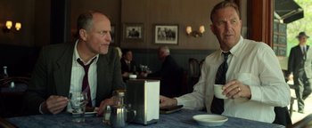 Movie still from “The Highwaymen” (2019), directed by John Lee Hancock – Two men sitting at a table with a cup of coffee; Medium shot, Low angle