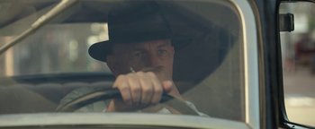Movie still from “The Highwaymen” (2019), directed by John Lee Hancock – A man in a hat is sitting in the drivers seat of a car; Close Up shot, Low angle