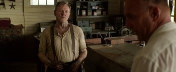 Movie still from “The Highwaymen” (2019), directed by John Lee Hancock – An older man standing in front of a table in a workshop; Medium shot, Over the shoulder angle