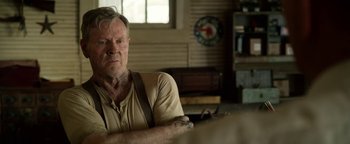 Movie still from “The Highwaymen” (2019), directed by John Lee Hancock – An older man sitting at a table in front of a clock; Close Up shot, Over the shoulder angle