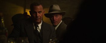 Movie still from “The Highwaymen” (2019), directed by John Lee Hancock – A man in a suit and a man in a hat; Close Up shot, Over the shoulder angle