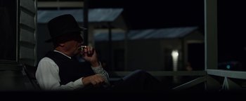 Movie still from “The Highwaymen” (2019), directed by John Lee Hancock – A man in a hat is smoking a cigarette in the dark; Medium shot, Over the shoulder angle