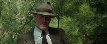 Movie still from “The Highwaymen” (2019), directed by John Lee Hancock – A man wearing a suit and a hat in a wooded area; Close Up shot, Low angle