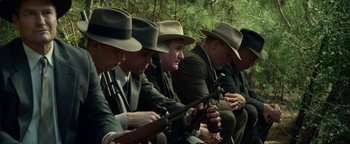 Movie still from “The Highwaymen” (2019), directed by John Lee Hancock – A group of men sitting next to each other holding guns; Medium shot, High angle