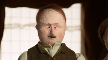 Movie still from “The House” (2022), directed by Paloma Baeza – A doll with blue eyes is wearing a vest; Extreme Close Up shot, High angle