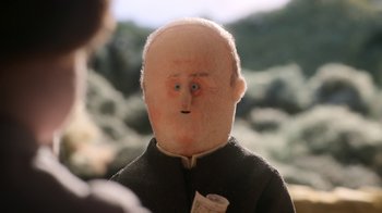 Movie still from “The House” (2022), directed by Paloma Baeza – A stuffed doll of an old man with a newspaper in his mouth; Extreme Close Up shot, Over the shoulder angle