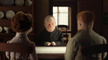 Movie still from “The House” (2022), directed by Paloma Baeza – A man with a bald head sitting in front of two other men; Medium shot, Over the shoulder angle