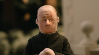 Movie still from “The House” (2022), directed by Paloma Baeza – A doll wearing a priest's outfit; Close Up shot, Low angle