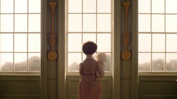 Movie still from “The House” (2022), directed by Paloma Baeza – A little girl standing in front of a window holding a stuffed animal; Medium shot, Low angle