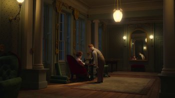 Movie still from “The House” (2022), directed by Paloma Baeza – A man and a woman are in a room with a rug; Wide shot, High angle