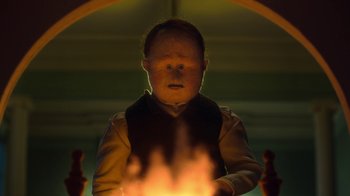 Movie still from “The House” (2022), directed by Paloma Baeza – A young man holding a candle in front of him; Close Up shot, Low angle