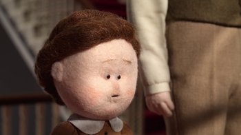 Movie still from “The House” (2022), directed by Paloma Baeza – A doll's face with a man in the background; Extreme Close Up shot, High angle