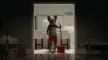 Movie still from “The House” (2022), directed by Paloma Baeza – A dog that is standing in a room with a mop in it's mouth; Wide shot, Low angle