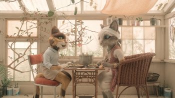 Movie still from “The House” (2022), directed by Paloma Baeza – A couple of cats are sitting at a table; Wide shot, High angle