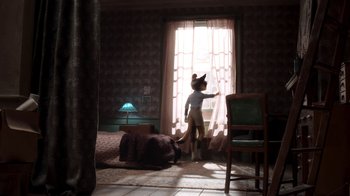 Movie still from “The House” (2022), directed by Paloma Baeza – A cat standing in front of a window looking outside; Wide shot, Over the shoulder angle