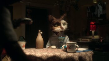 Movie still from “The House” (2022), directed by Paloma Baeza – A cat sitting at a table with a vase and a cup; Medium shot, Over the shoulder angle