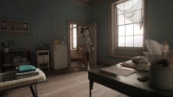 Movie still from “The House” (2022), directed by Paloma Baeza – A person with a cat mask in a room; Wide shot, High angle