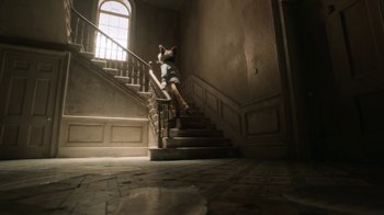 Movie still from “The House” (2022), directed by Paloma Baeza – A dog sitting on the steps of a staircase; Wide shot, Low angle