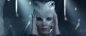 Movie still from “The Huntsman: Winter's War” (2016), directed by Cedric Nicolas-Troyan – A woman wearing a white feather mask with her hands on her face; Close Up shot, Low angle