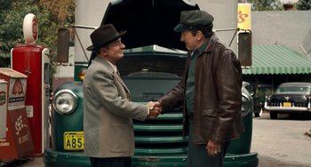 Movie still from “The Irishman” (2019), directed by Martin Scorsese – Two men shaking hands in front of an old truck; Medium shot, Over the shoulder angle