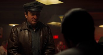 Movie still from “The Irishman” (2019), directed by Martin Scorsese – A man wearing a hat and a leather jacket; Medium shot, Over the shoulder angle