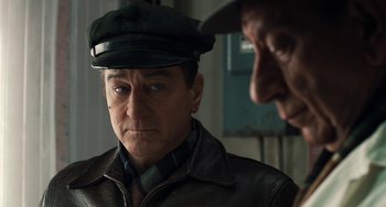 Movie still from “The Irishman” (2019), directed by Martin Scorsese – A man wearing a leather jacket and a hat; Close Up shot, Over the shoulder angle