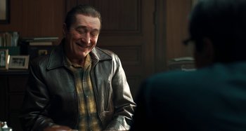 Movie still from “The Irishman” (2019), directed by Martin Scorsese – An older man sitting at a table in a room; Medium shot, Over the shoulder angle
