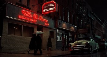 Movie still from “The Irishman” (2019), directed by Martin Scorsese – Two people walking down the street under an umbrella at night; Wide shot, Low angle