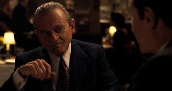 Movie still from “The Irishman” (2019), directed by Martin Scorsese – An older man wearing a suit and tie sitting at a table in a restaurant; Close Up shot, Over the shoulder angle