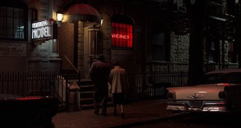 Movie still from “The Irishman” (2019), directed by Martin Scorsese – A man and a woman walking down the sidewalk; Wide shot, High angle