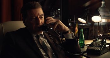 Movie still from “The Irishman” (2019), directed by Martin Scorsese – A man talking on a phone while sitting at a table; Medium shot, High angle