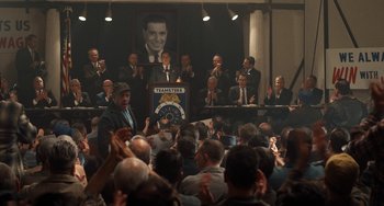 Movie still from “The Irishman” (2019), directed by Martin Scorsese – A crowd of people sitting in front of a microphone; Wide shot, High angle