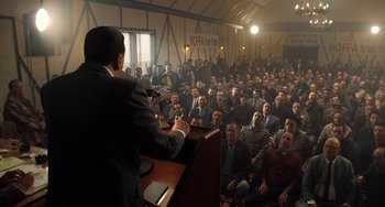 Movie still from “The Irishman” (2019), directed by Martin Scorsese – A crowd of people sitting and standing in front of a podium; Wide shot, High angle