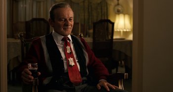 Movie still from “The Irishman” (2019), directed by Martin Scorsese – An older man sitting in a chair wearing a red tie; Medium shot, Over the shoulder angle