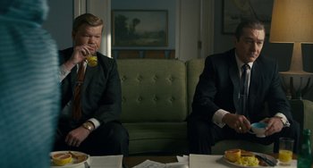 Movie still from “The Irishman” (2019), directed by Martin Scorsese – Two men in suits sitting on couches in a room; Medium shot, High angle