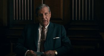 Movie still from “The Irishman” (2019), directed by Martin Scorsese – An older man wearing a suit and tie holding papers; Close Up shot, Over the shoulder angle