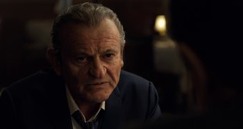 Movie still from “The Irishman” (2019), directed by Martin Scorsese – An older man wearing a suit and tie looking at the camera; Close Up shot, Over the shoulder angle