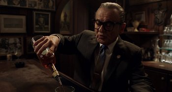Movie still from “The Irishman” (2019), directed by Martin Scorsese – An older man pouring a drink into a wine glass; Medium shot, Low angle