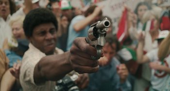 Movie still from “The Irishman” (2019), directed by Martin Scorsese – A man holding a gun in front of a group of onlookers; Close Up shot, Low angle