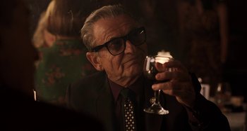 Movie still from “The Irishman” (2019), directed by Martin Scorsese – An old man wearing a suit and tie holding a glass of wine; Close Up shot, Low angle