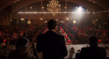 Movie still from “The Irishman” (2019), directed by Martin Scorsese – A man standing in front of an audience at a party; Wide shot, High angle