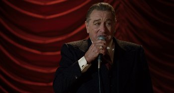 Movie still from “The Irishman” (2019), directed by Martin Scorsese – An older man is holding a microphone up to his mouth; Close Up shot, High angle