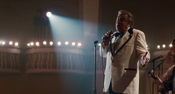 Movie still from “The Irishman” (2019), directed by Martin Scorsese – A man in a white suit holding a microphone; Medium shot, Low angle