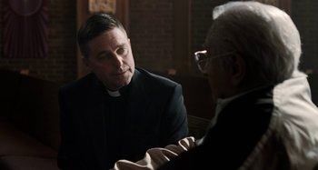 Movie still from “The Irishman” (2019), directed by Martin Scorsese – A man in a clerical collar talking to another man; Close Up shot, Over the shoulder angle