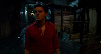 Movie still from “Only God Forgives” (2013), directed by Nicolas Winding Refn – A man in a red shirt is standing outside; Medium shot, Low angle