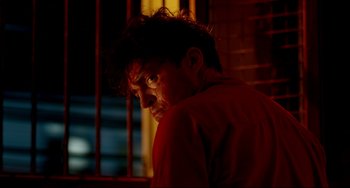 Movie still from “Only God Forgives” (2013), directed by Nicolas Winding Refn – A man in a red shirt is looking out a window; Close Up shot, Low angle