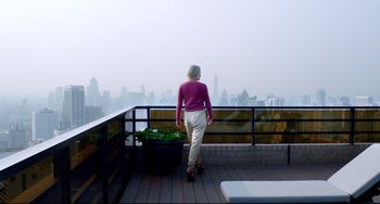 Movie still from “Only God Forgives” (2013), directed by Nicolas Winding Refn – A woman standing on a balcony looking out at a city; Wide shot, High angle