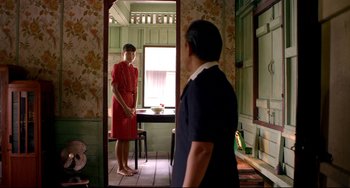 Movie still from “Only God Forgives” (2013), directed by Nicolas Winding Refn – A man and a woman standing in front of a table in a room; Medium shot, Over the shoulder angle