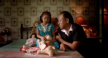 Movie still from “Only God Forgives” (2013), directed by Nicolas Winding Refn – A man and a little girl sitting on a bed with stuffed animals; Medium shot, High angle